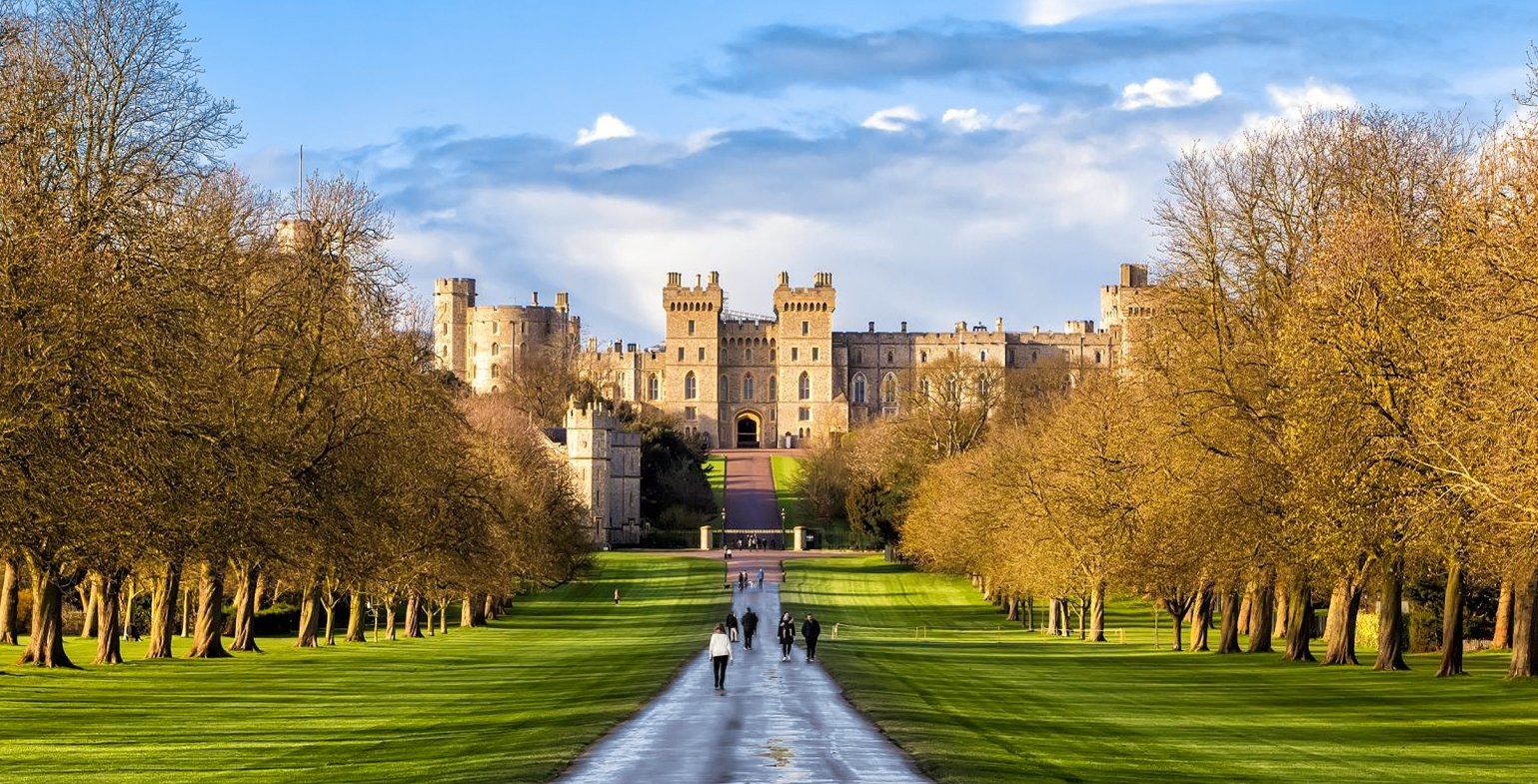 Windsor Castle with visitors walking along the Long Walk path.