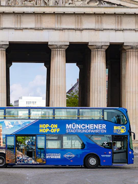 Blue double-decker bus for Munich hop-on-hop-off tour in front of historic columns.