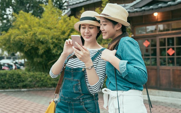 Two travelers using a smartphone to navigate with ICOCA IC Card in Japan.