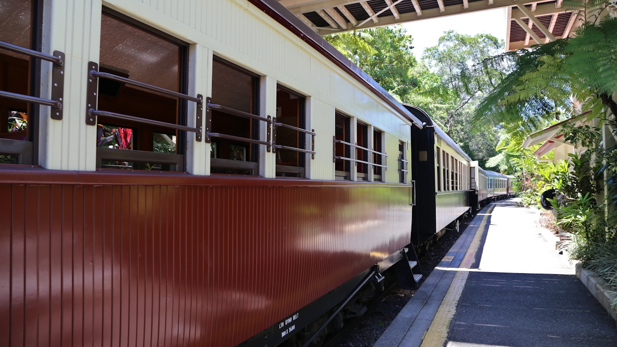 Kuranda railway station with vintage train on platform surrounded by lush greenery.