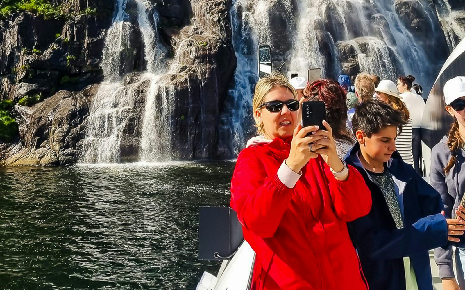 Guests on a boat cruise through Lysefjord, Norway, with scenic views of cliffs and waterfalls.