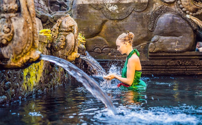 Woman participating in a purification ritual at Tirta Empul Temple, Bali.