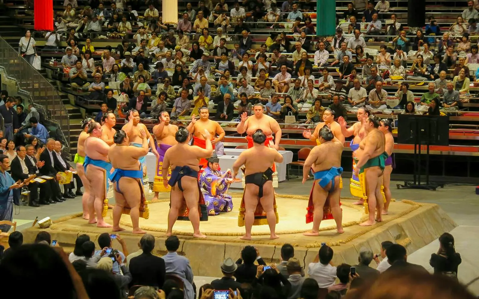 Sumo wrestlers in a ring at the Grand Sumo Tournament, Japan, with audience watching.
