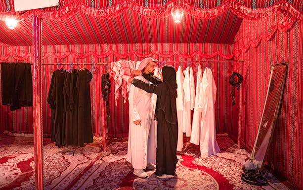 Traditional clothing fitting in a red tent during Abu Dhabi evening desert safari.
