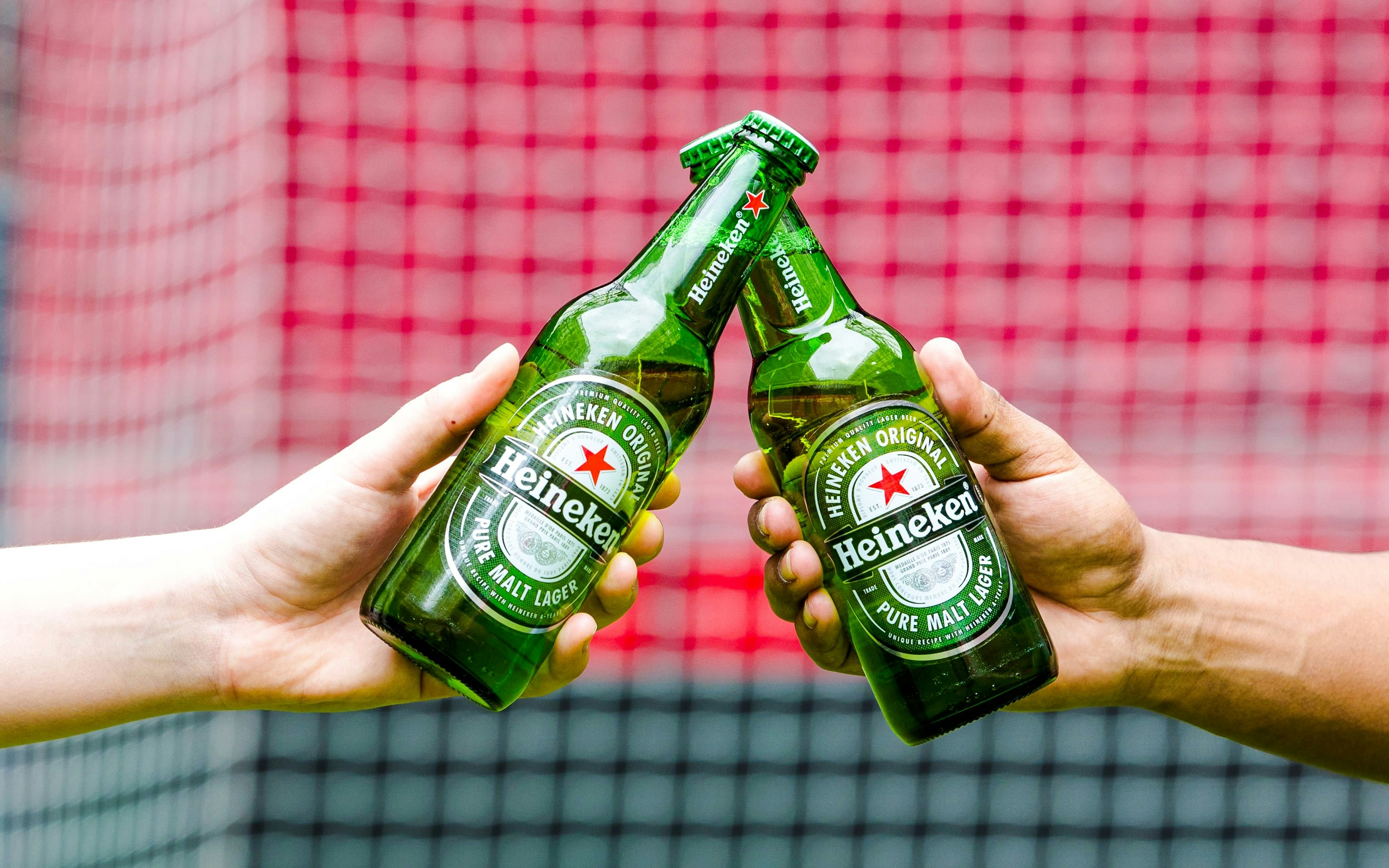 Heineken bottles clinking in front of a football net at the Heineken Experience.
