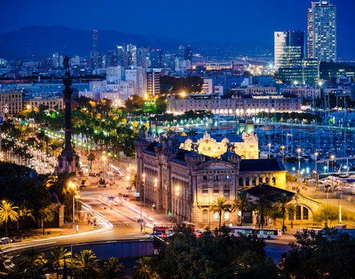 Barcelona cityscape at night with Columbus Monument and Port Vell marina.