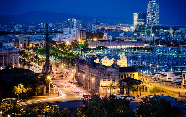 Barcelona cityscape at night with Columbus Monument and Port Vell marina.