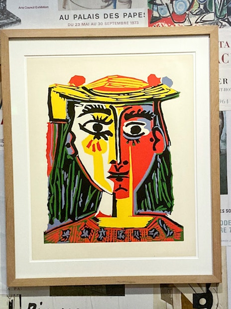 Framed Picasso painting on a wall of exhibition posters at the Picasso Museum.