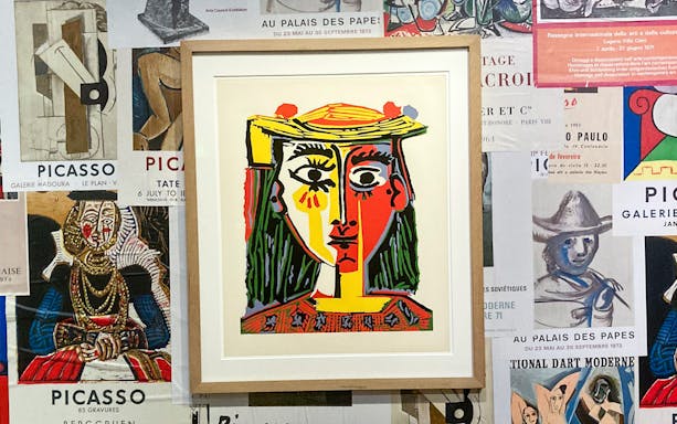 Framed Picasso painting on a wall of exhibition posters at the Picasso Museum.