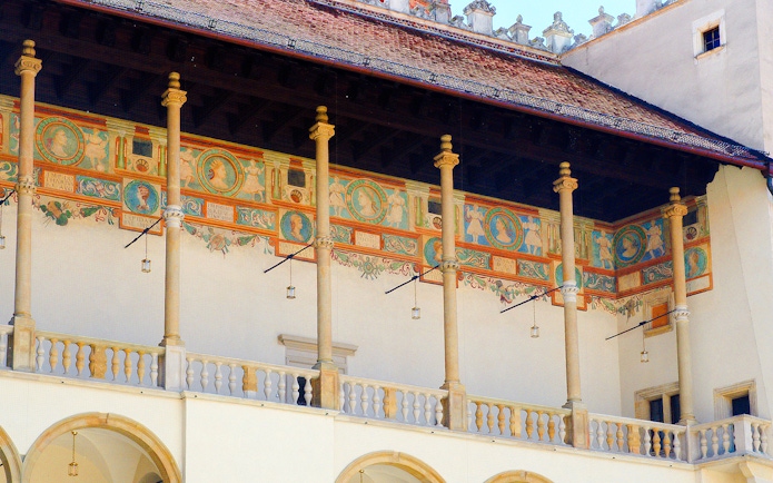 Wawel Cathedral's Renaissance courtyard with decorative frescoes and columns.