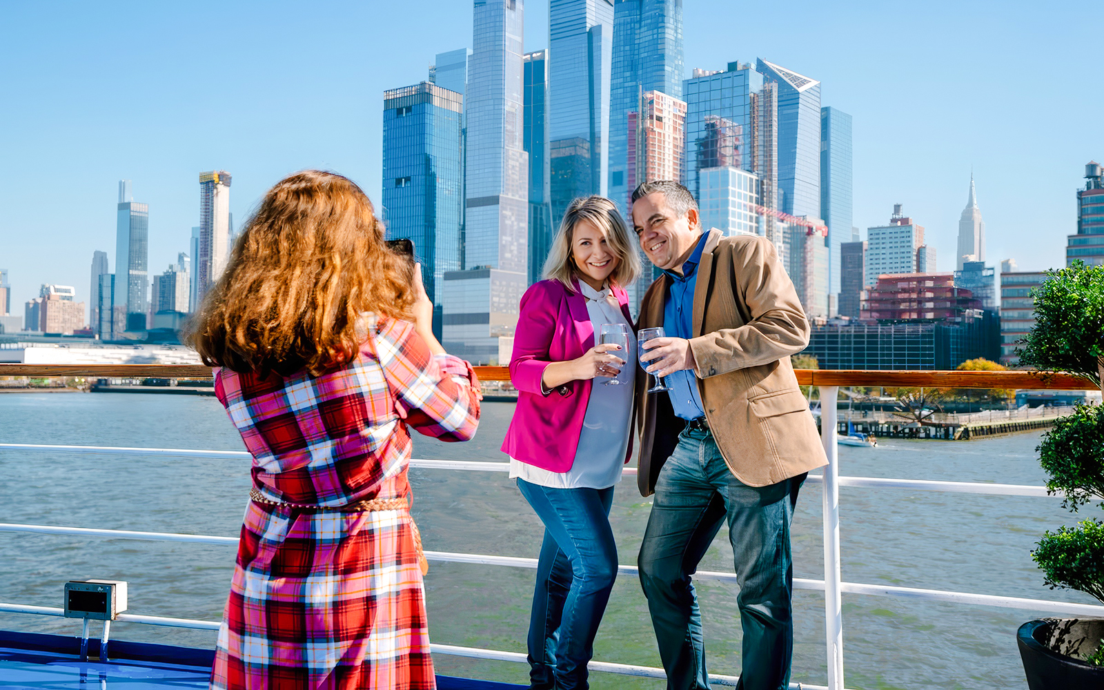 Couple enjoying drinks on a luxury glass boat cruise with New York City skyline.