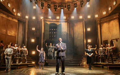 Stage performance of Hadestown in West End theater with cast on illuminated set.