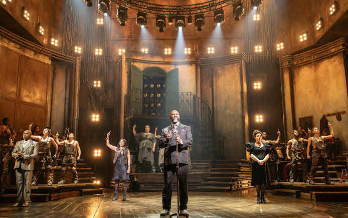Stage performance of Hadestown in West End theater with cast on illuminated set.