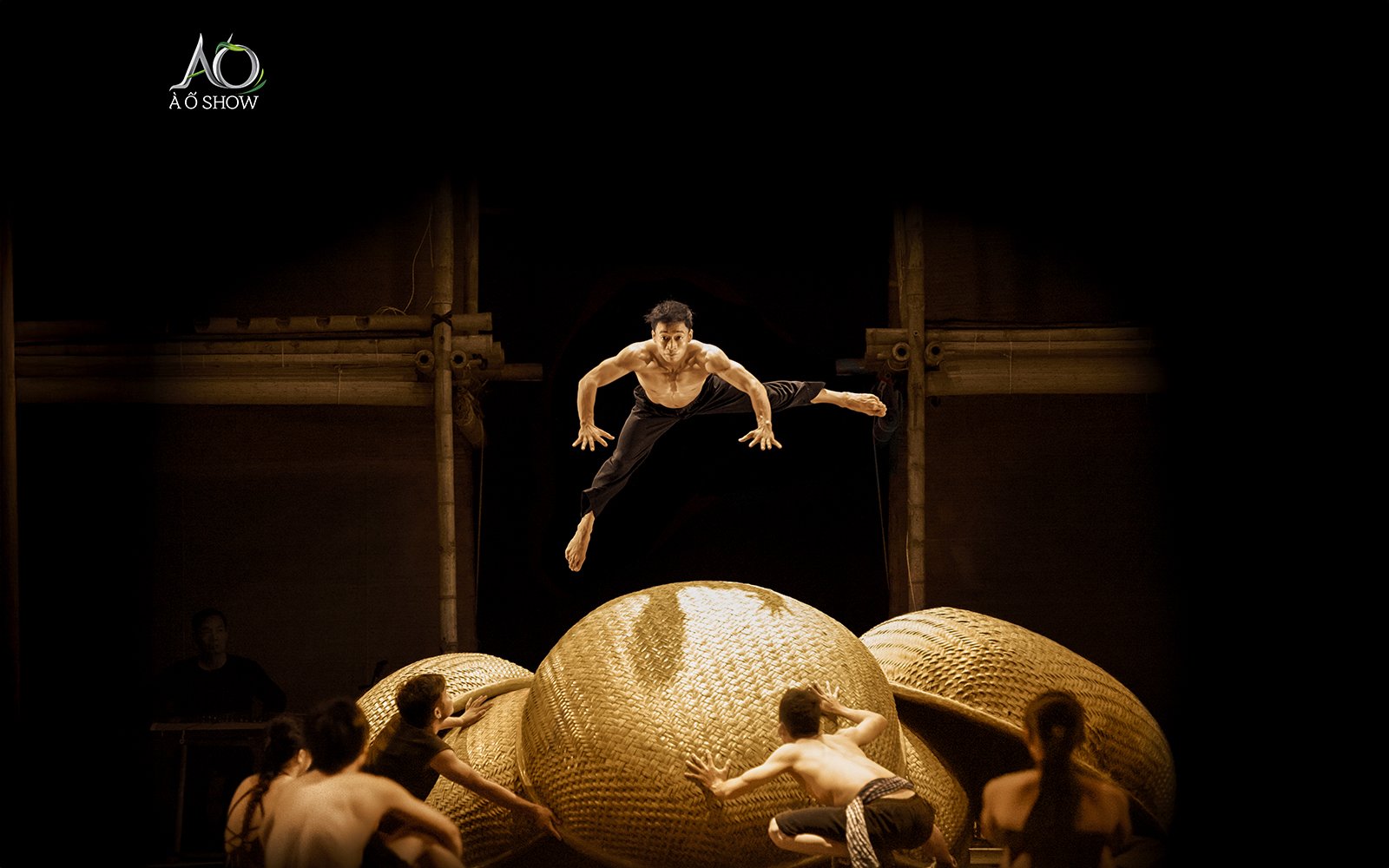 Performers leaping on stage at AO SHOW with bamboo props.