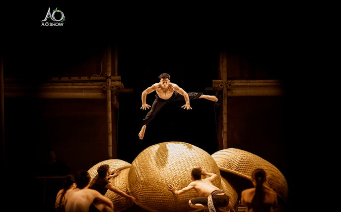 Performers leaping on stage at AO SHOW with bamboo props.