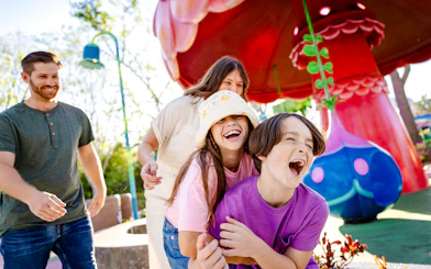 Children laughing and playing at Universal Kids Resort with colorful mushroom structures.