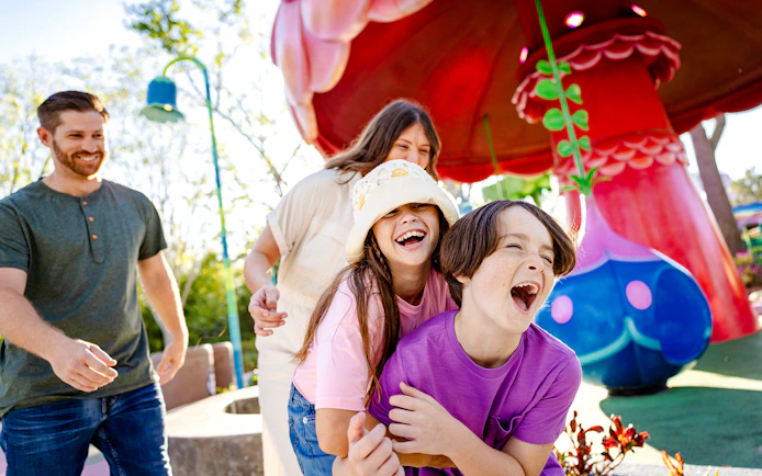 Children laughing and playing at Universal Kids Resort with colorful mushroom structures.