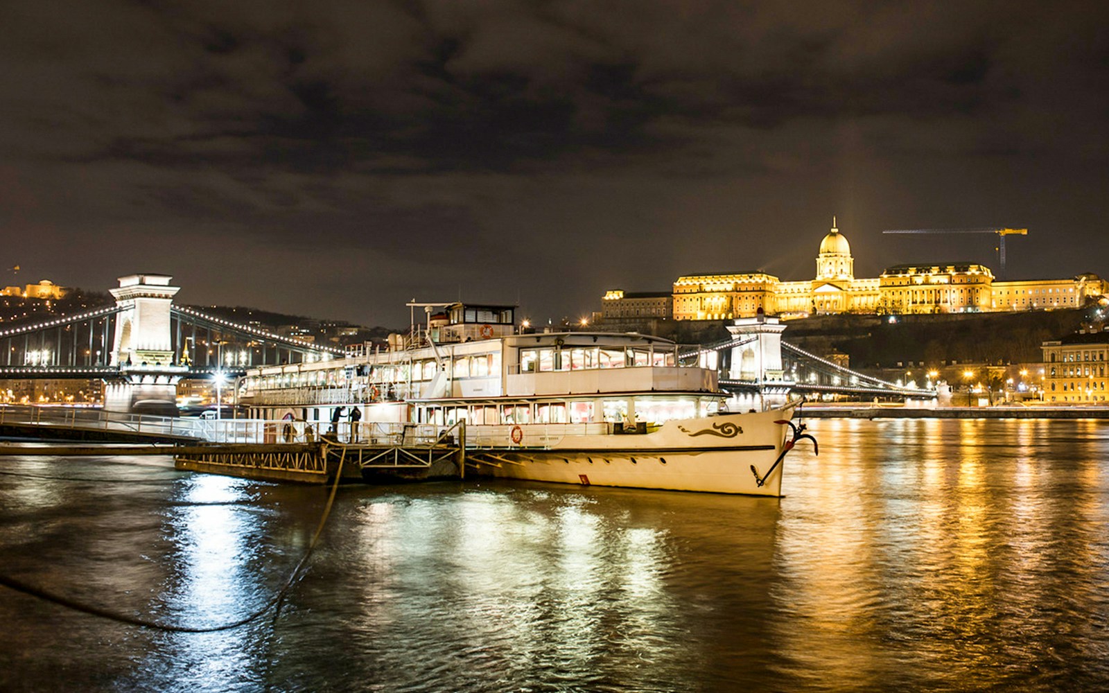 Sightseeing cruise boat on the Danube River with Budapest's Parliament building in the background.
