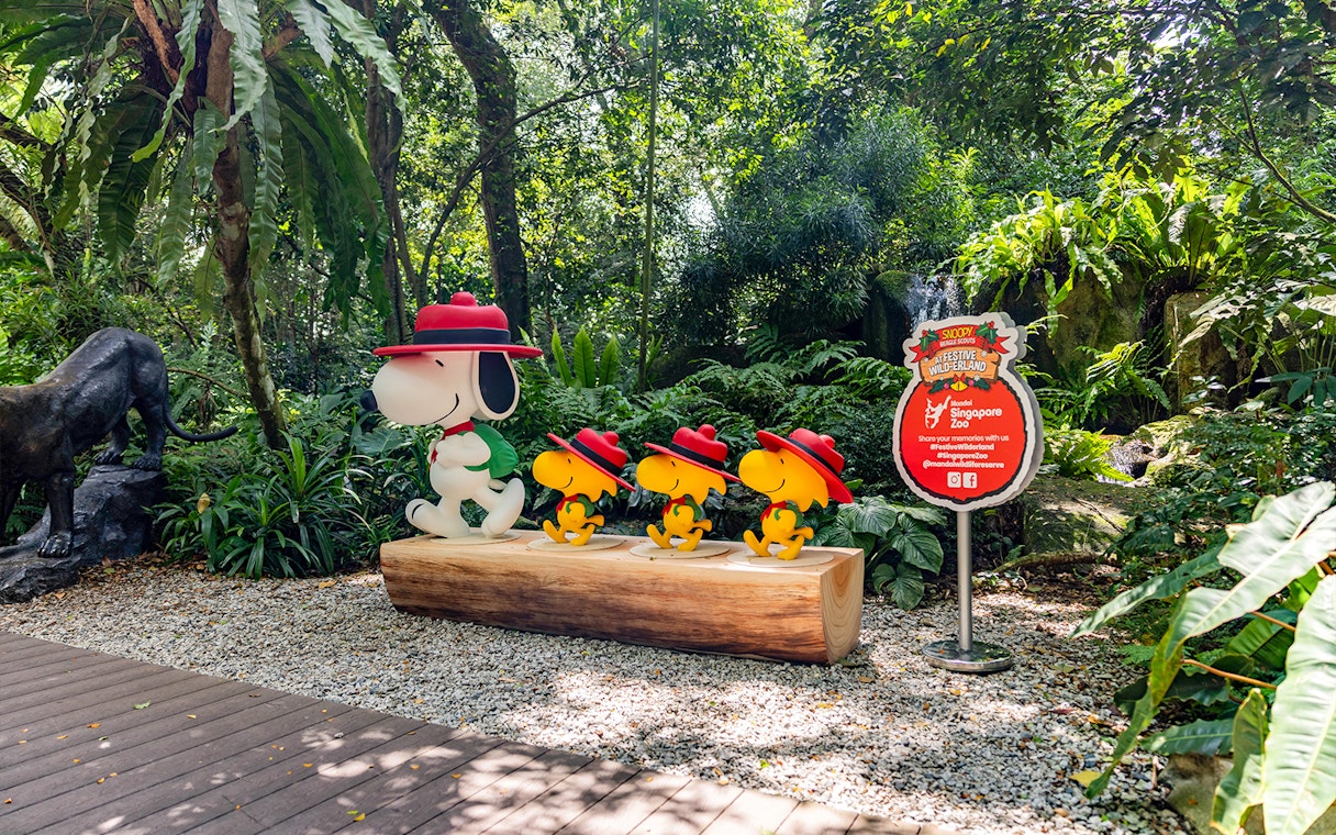 Snoopy and Beagle Scouts statues at Singapore Zoo amidst lush greenery.