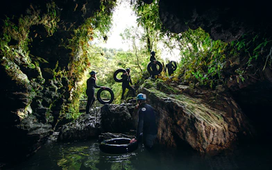 Adventurers with tubes exploring a cave during a black water rafting tour in Waitomo.