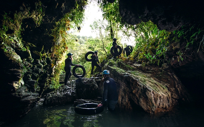 Adventurers with tubes exploring a cave during a black water rafting tour in Waitomo.