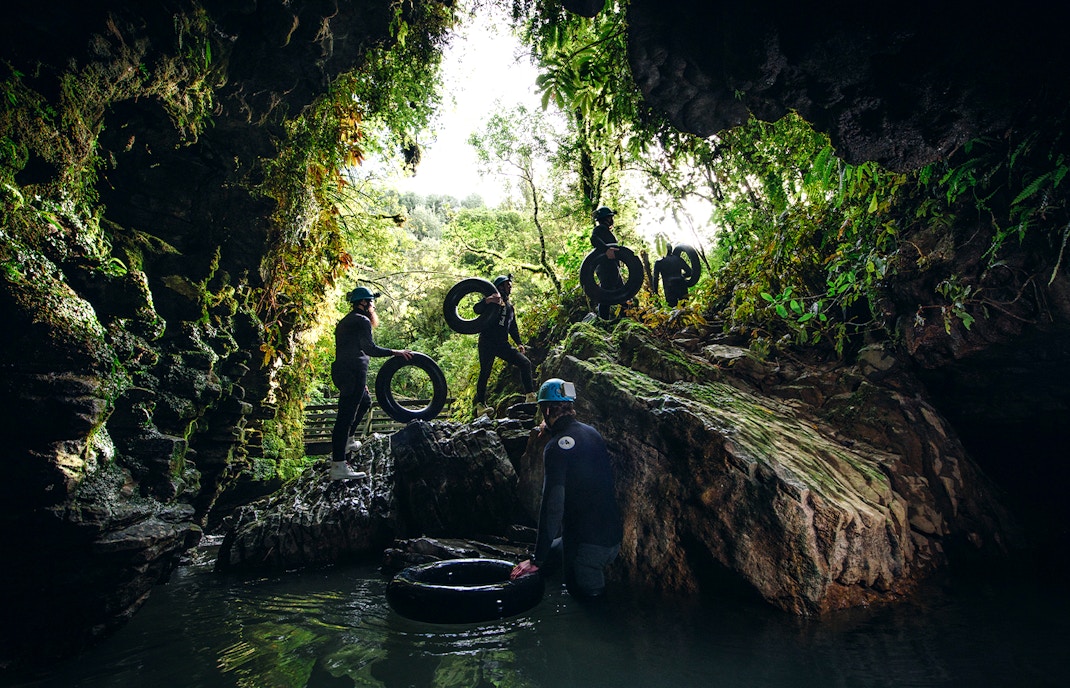 Adventurers with tubes exploring a cave during a black water rafting tour in Waitomo.