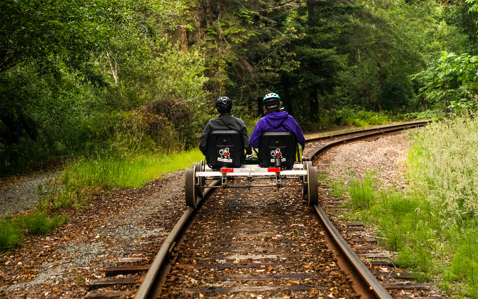Two people riding railbikes on a forested track towards Glen Blair Bar.