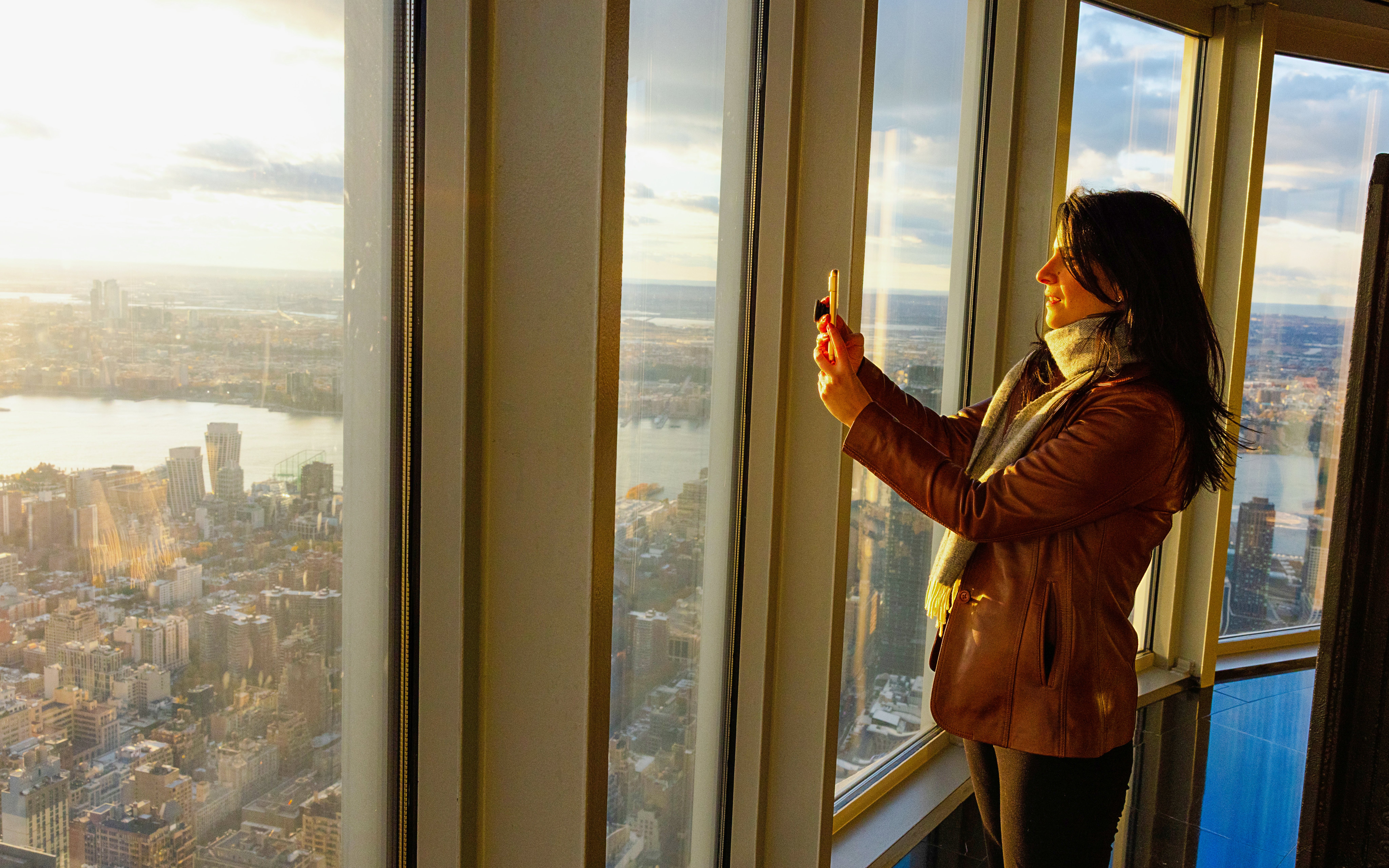 Guest taking photo at Empire State Building observatory with city view.