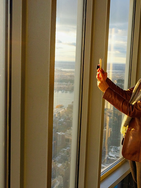 Guest taking photo at Empire State Building observatory with city view.