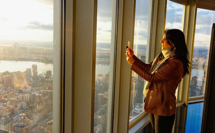 Guest taking photo at Empire State Building observatory with city view.