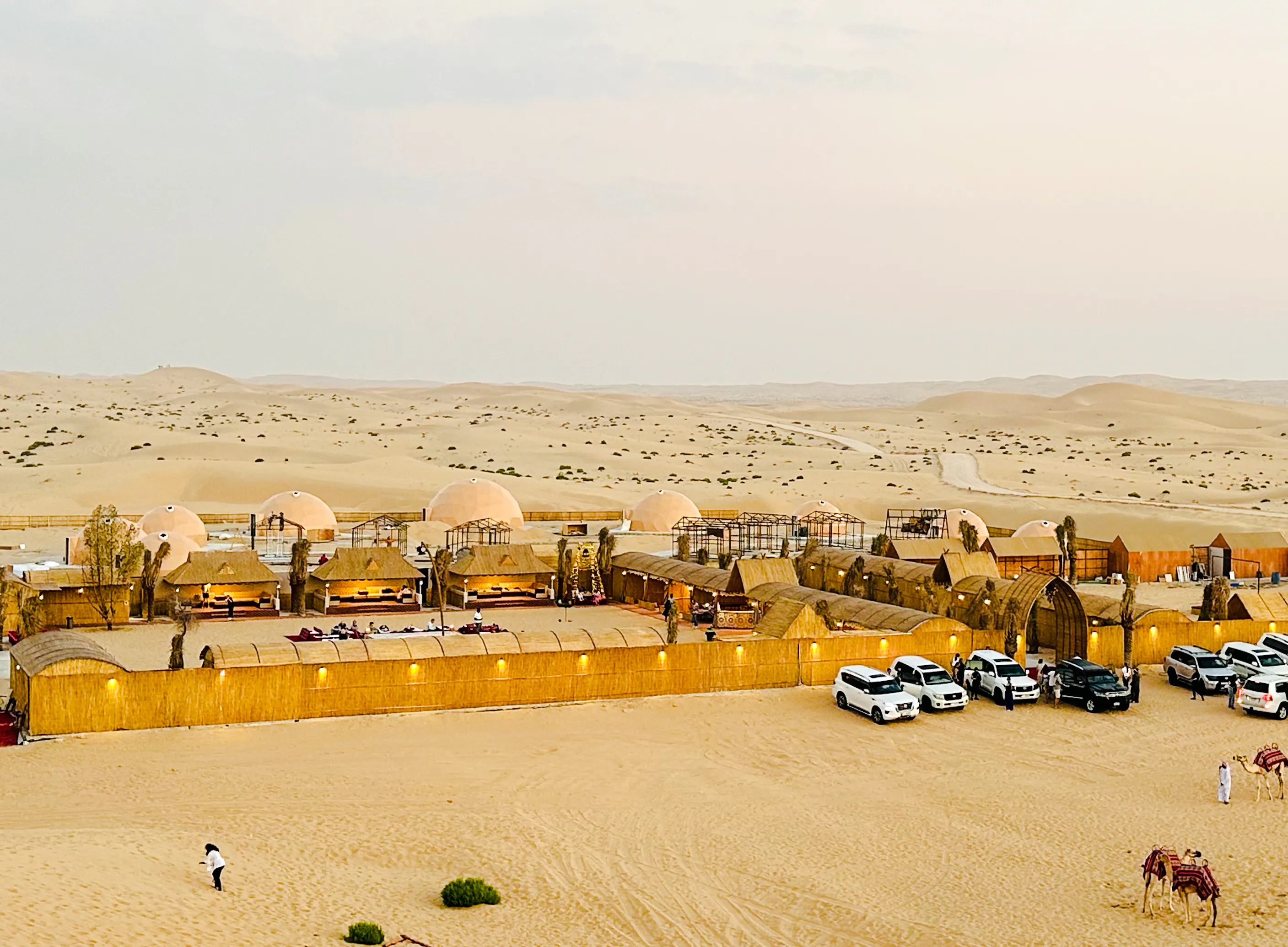 Desert camp with domed tents and parked SUVs in Abu Dhabi for a private safari and sandboarding experience.