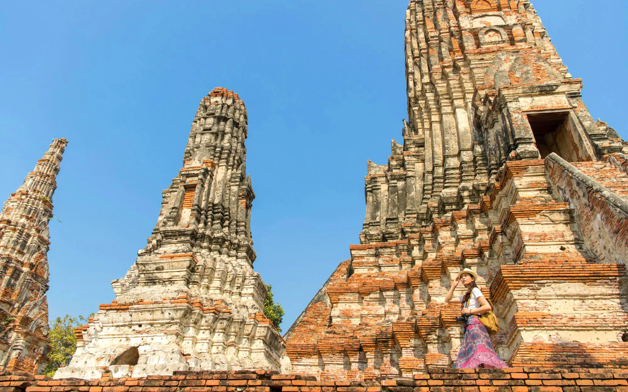 Ancient brick temples of Ayutthaya with a visitor exploring the historic site.