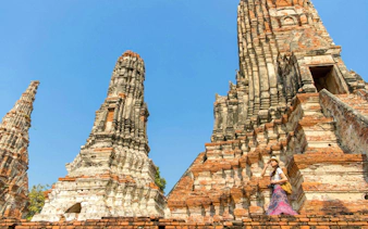 Ancient brick temples of Ayutthaya with a visitor exploring the historic site.