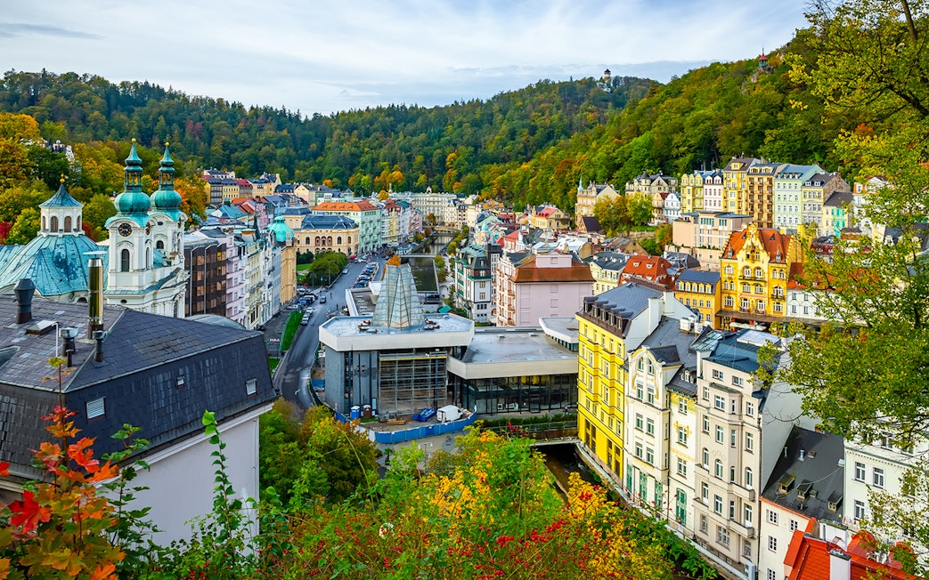 Karlovy Vary cityscape with colorful buildings and forested hills, view from Watchtower Diana.