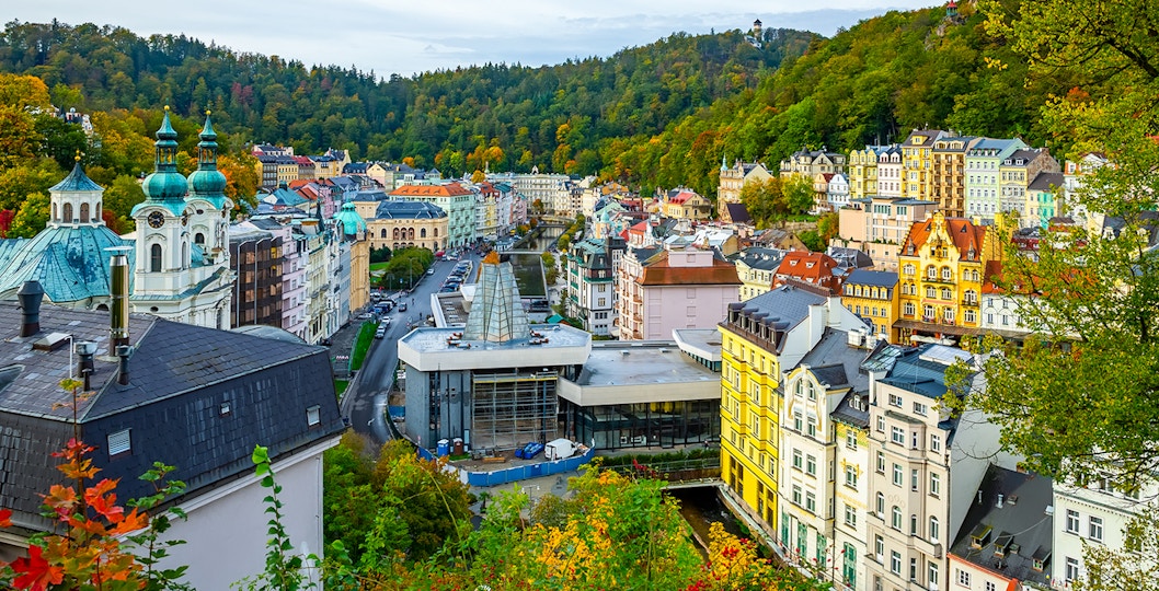 Karlovy Vary cityscape with colorful buildings and forested hills, view from Watchtower Diana.