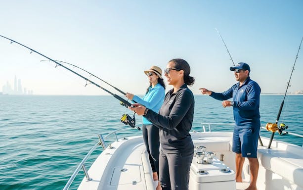 Women fishing with guide on boat, Dubai skyline in background.
