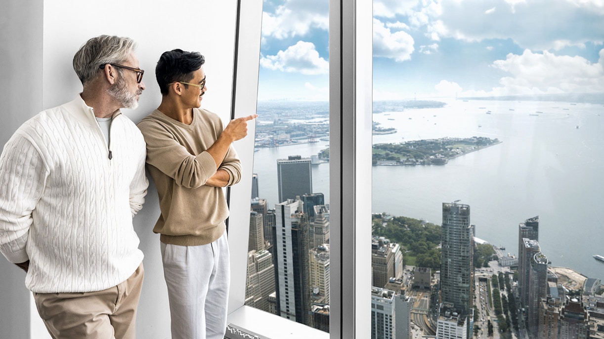 Visitors enjoying the view from One World Observatory, overlooking New York City skyline and harbor.