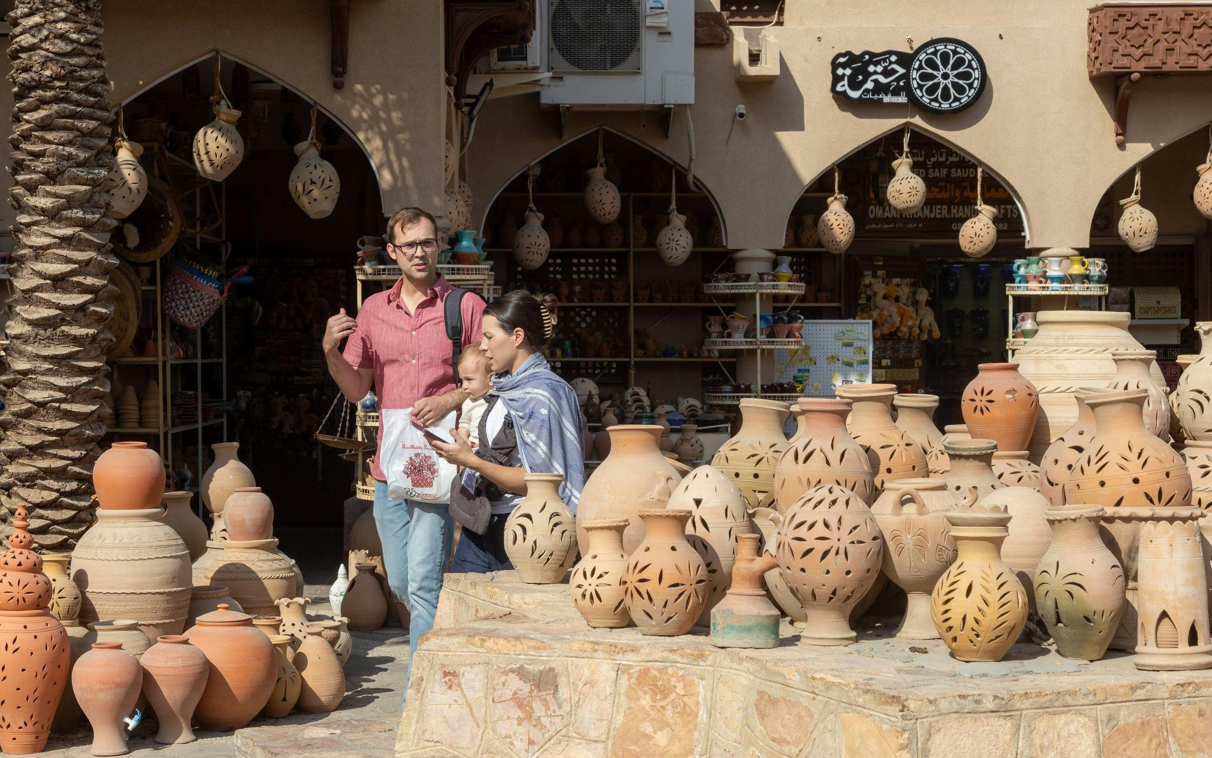 Tourists exploring pottery at Nizwa Souk, Oman.