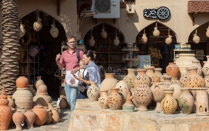 Tourists exploring pottery at Nizwa Souk, Oman.