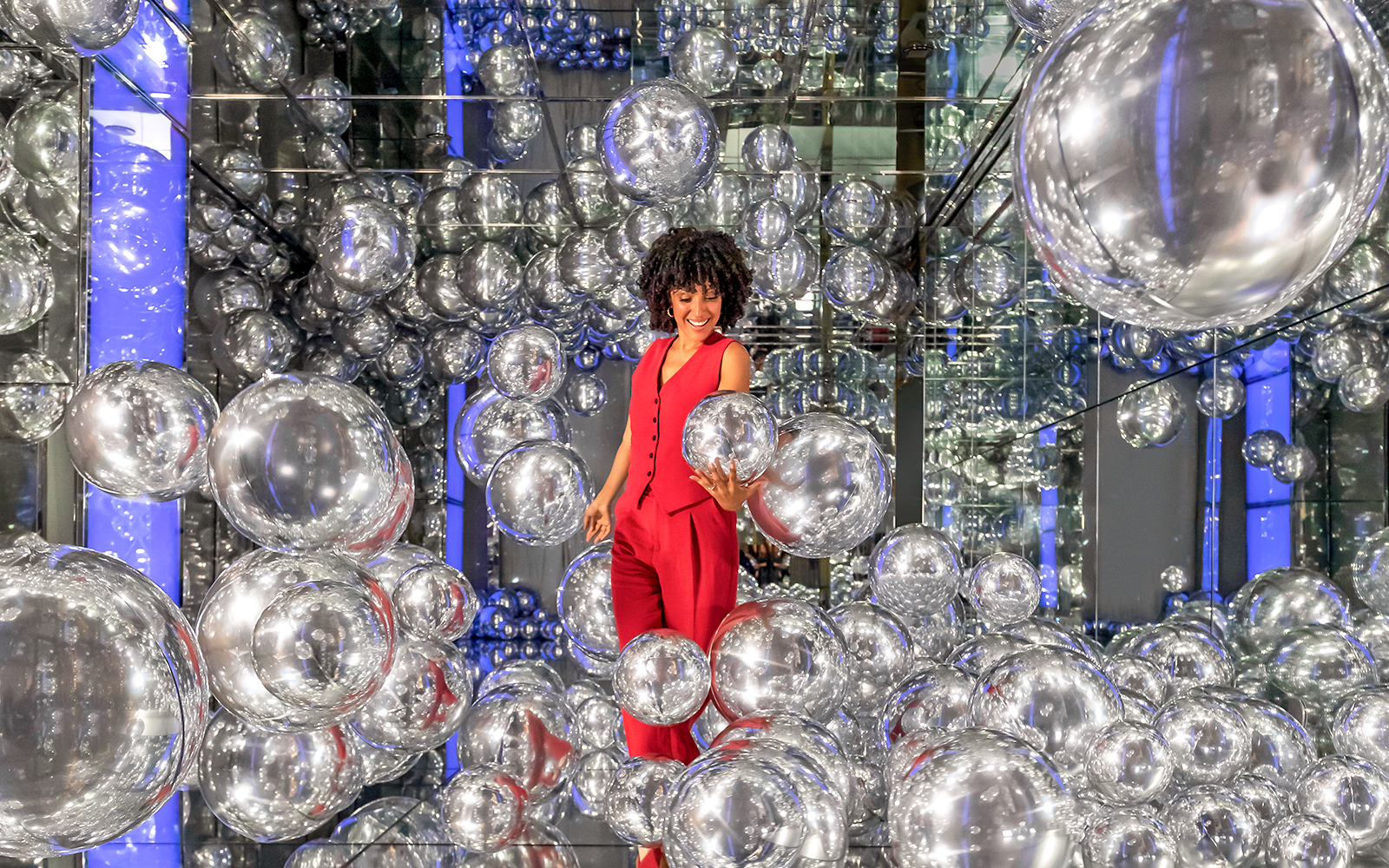 Woman exploring mirrored room with silver spheres at Summit One Vanderbilt.