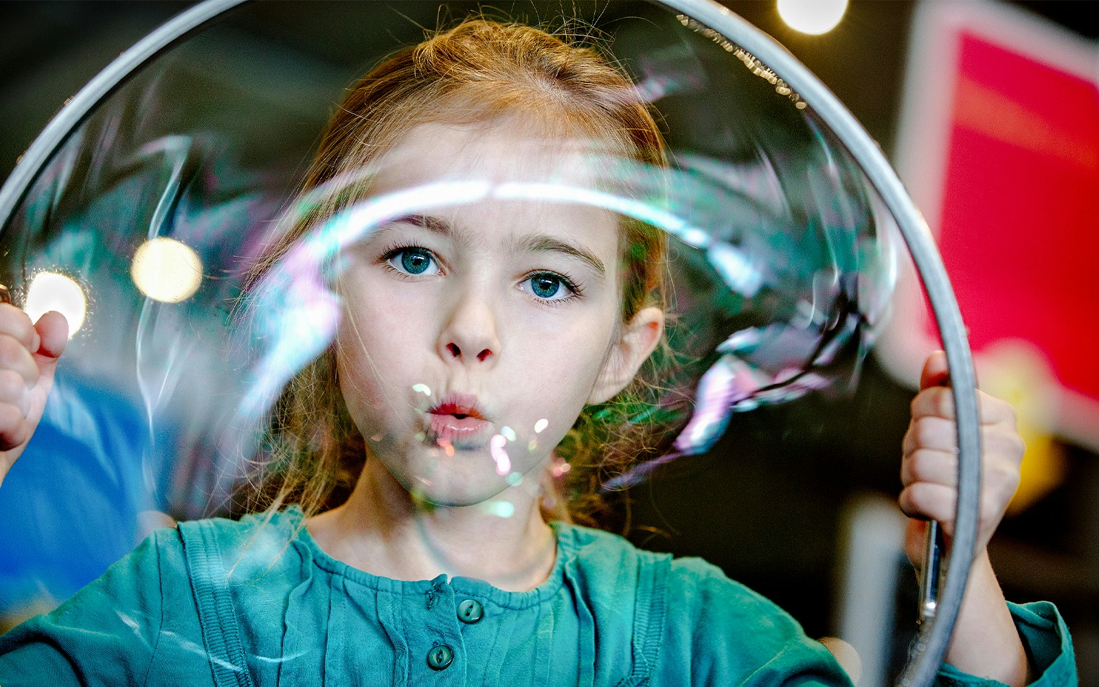 Child blowing a giant bubble at NEMO Science Museum exhibit.