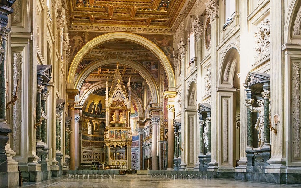Interior view of the Archbasilica of Saint John Lateran in Rome, featuring ornate columns and altar.