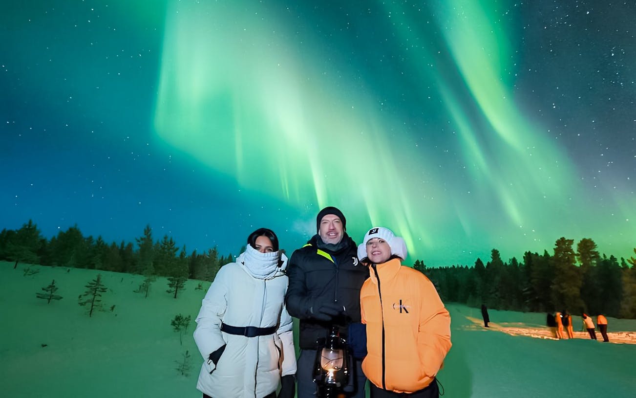Guests viewing Northern Lights on a snowy landscape during Discovery Tour.