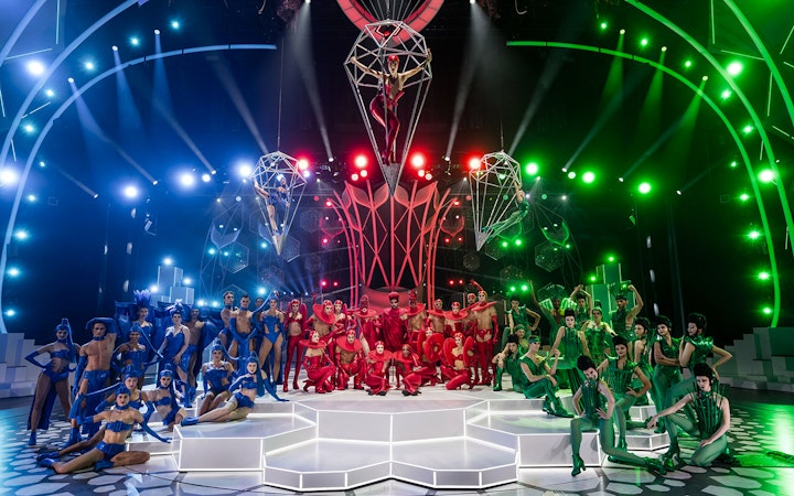 Performers in colorful costumes on stage at the FALLING | IN LOVE Grand Show, Friedrichstadt Palast.