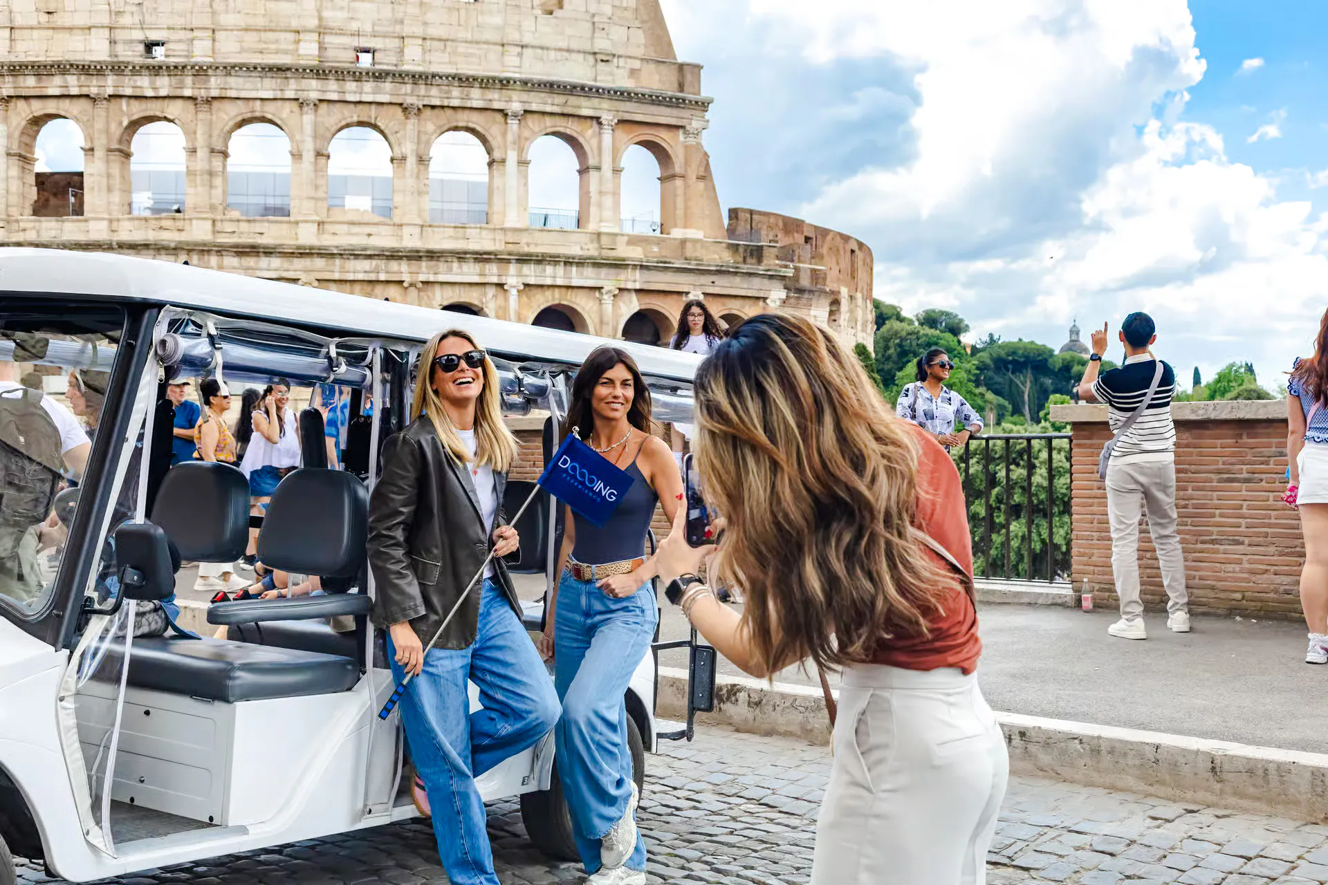 Golf cart tour near the Colosseum in Rome with tourists enjoying the view.