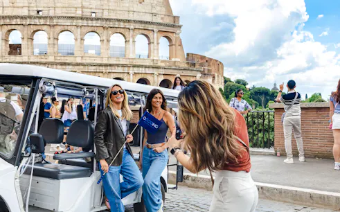 Golf cart tour near the Colosseum in Rome with tourists enjoying the view.