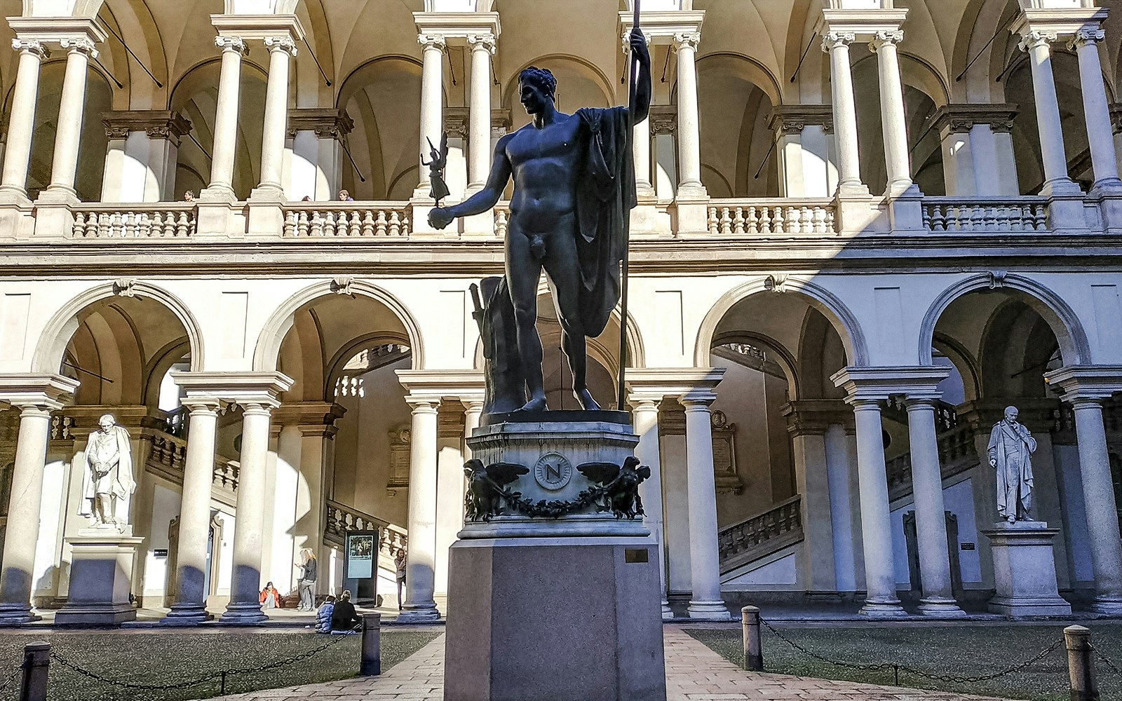 Statue of Napoleon as Mars the Peacemaker in a courtyard, with the Pinacoteca di Brera building in the background.