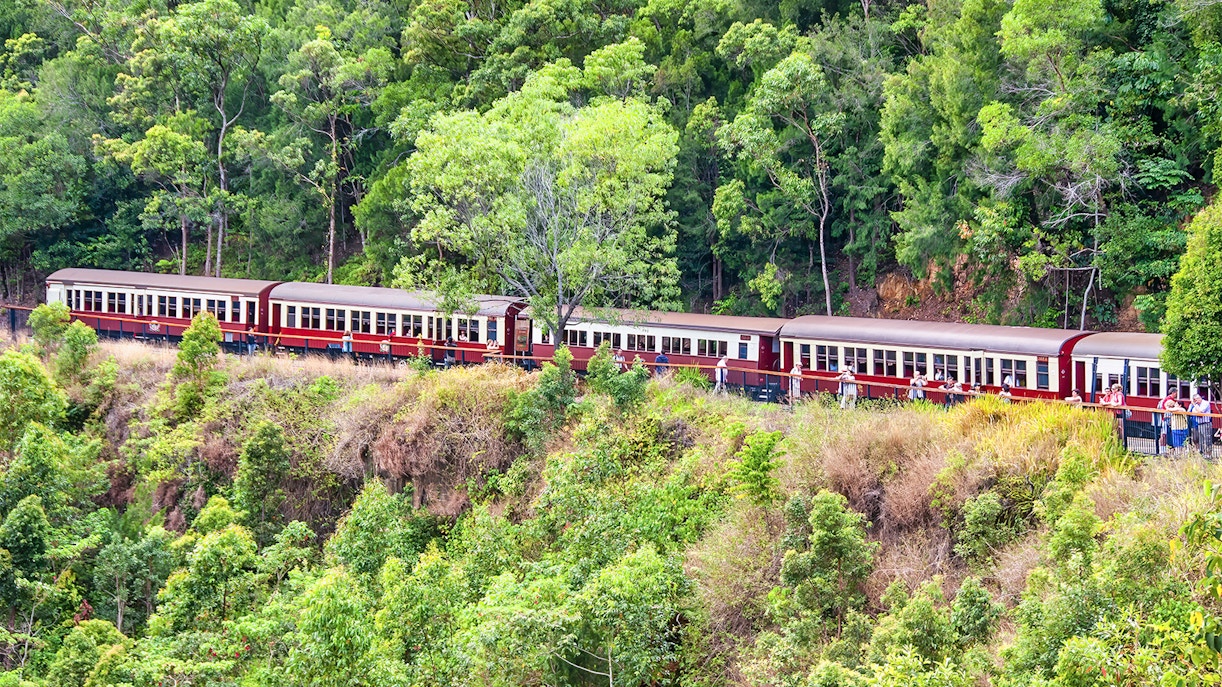 Kuranda Scenic Railway train traveling through lush rainforest landscape.