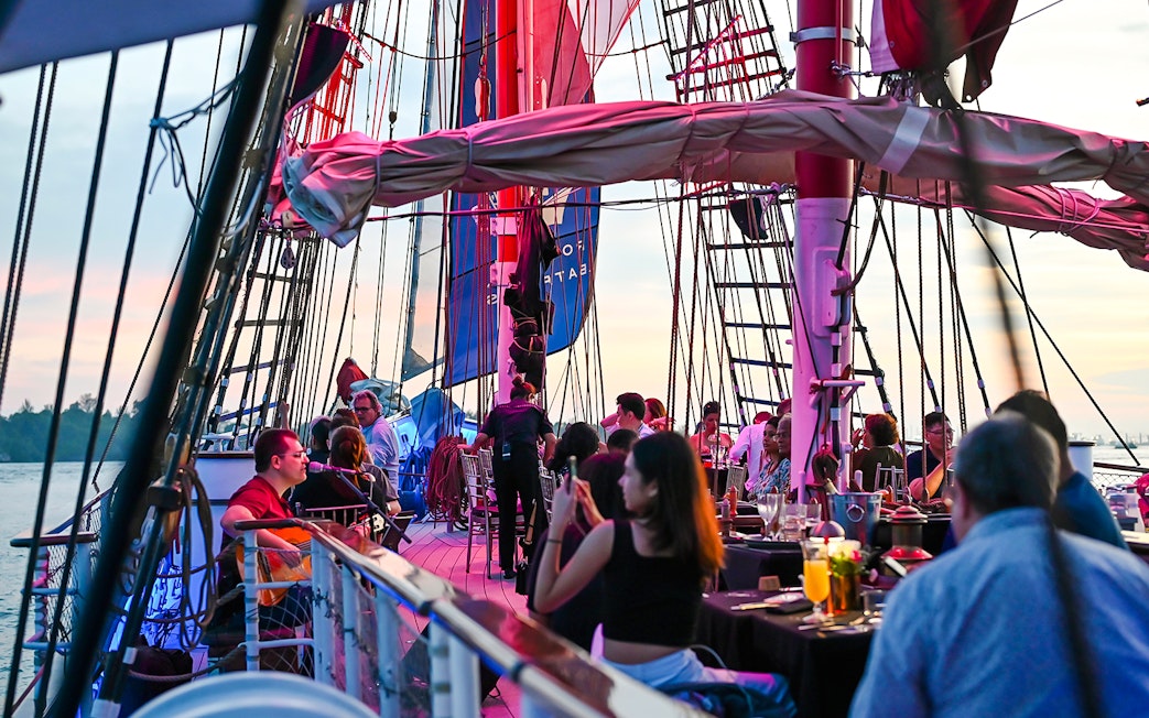 Guests dining on the deck of The Royal Albatross during a sunset cruise.