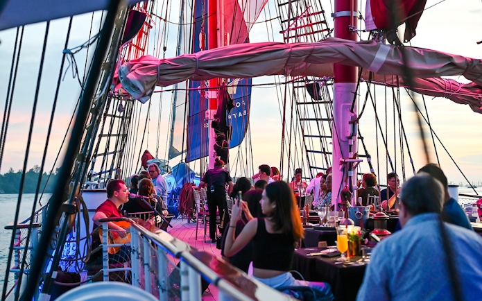 Guests dining on the deck of The Royal Albatross during a sunset cruise.